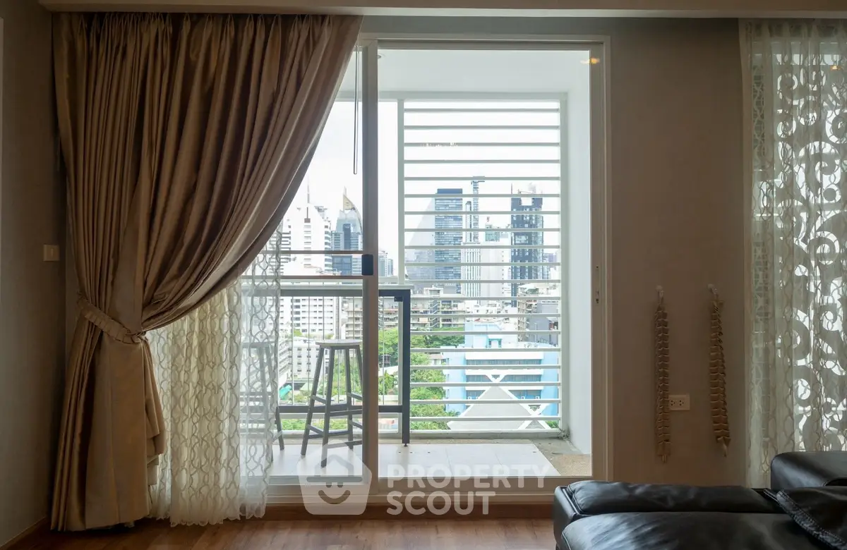 Luxurious living room with balcony offering stunning city skyline views, elegant curtains, and modern decor.