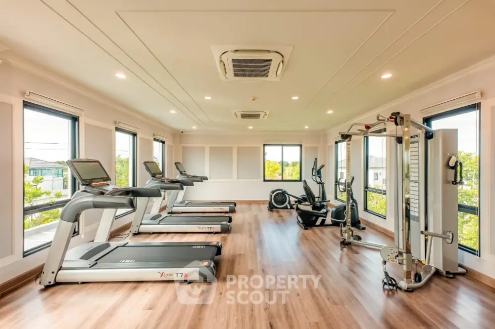 Spacious modern gym with state-of-the-art equipment and large windows offering scenic views.