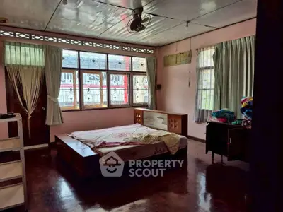 Spacious bedroom with large windows and wooden flooring