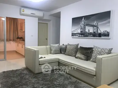 Stylish living room with modern sectional sofa and wall art, adjacent to a cozy kitchen.