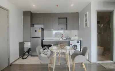 Modern kitchen with dining area, washing machine, and sleek cabinetry in open layout.