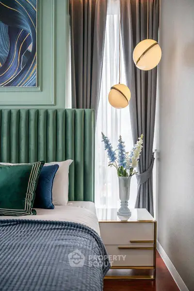 Luxurious bedroom with elegant decor, featuring plush headboard, stylish lighting, and chic bedside table.