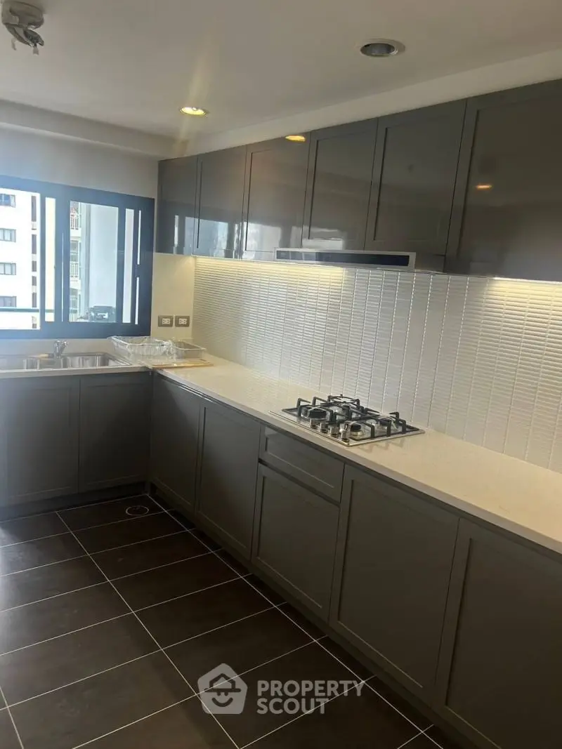 Modern kitchen with sleek cabinetry and gas stove in a high-rise apartment.