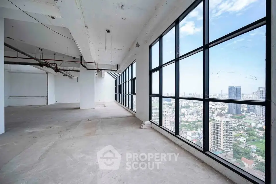 Spacious corner unit with floor-to-ceiling windows offering panoramic city views in a modern high-rise building.