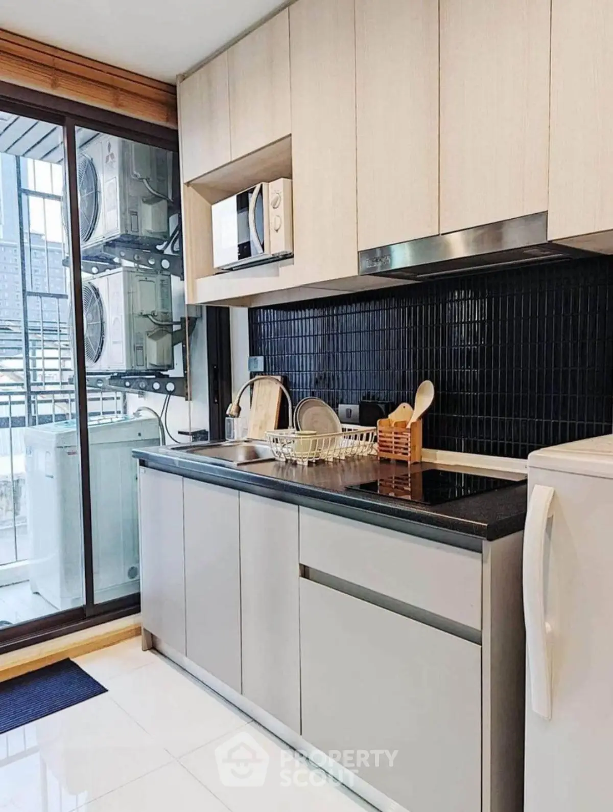 Modern kitchen with sleek cabinetry, microwave, and washing machine in a high-rise apartment.