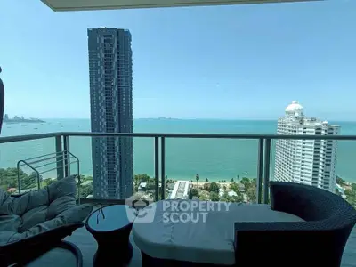 Stunning ocean view from high-rise balcony with modern seating, perfect for relaxation.
