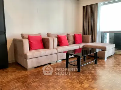 Spacious living room with stylish beige sectional sofa and red cushions, featuring elegant parquet flooring.