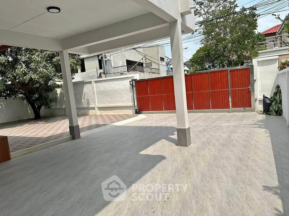 Spacious modern driveway with tiled flooring and red gate, perfect for multiple vehicles.