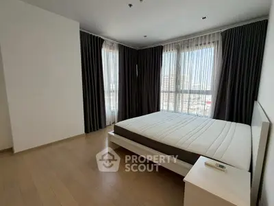 Spacious bedroom with large windows and modern decor in a high-rise apartment.