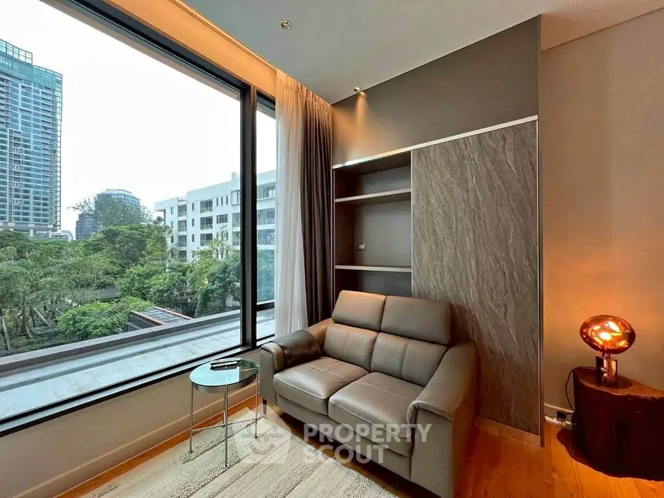 Modern living room with large window and cozy seating, offering a serene view of the cityscape.