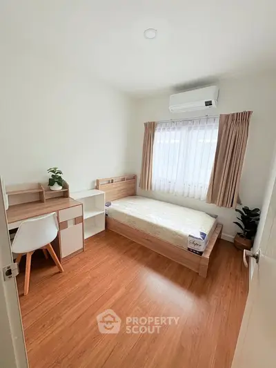 Cozy bedroom with wooden flooring, single bed, desk, and air conditioning.