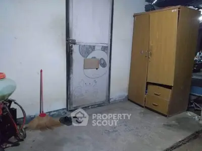 Simple room with a wooden wardrobe and broom, showcasing basic living conditions.