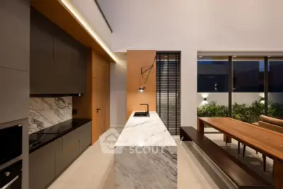 Modern kitchen with marble island and open layout, featuring sleek cabinetry and natural light.
