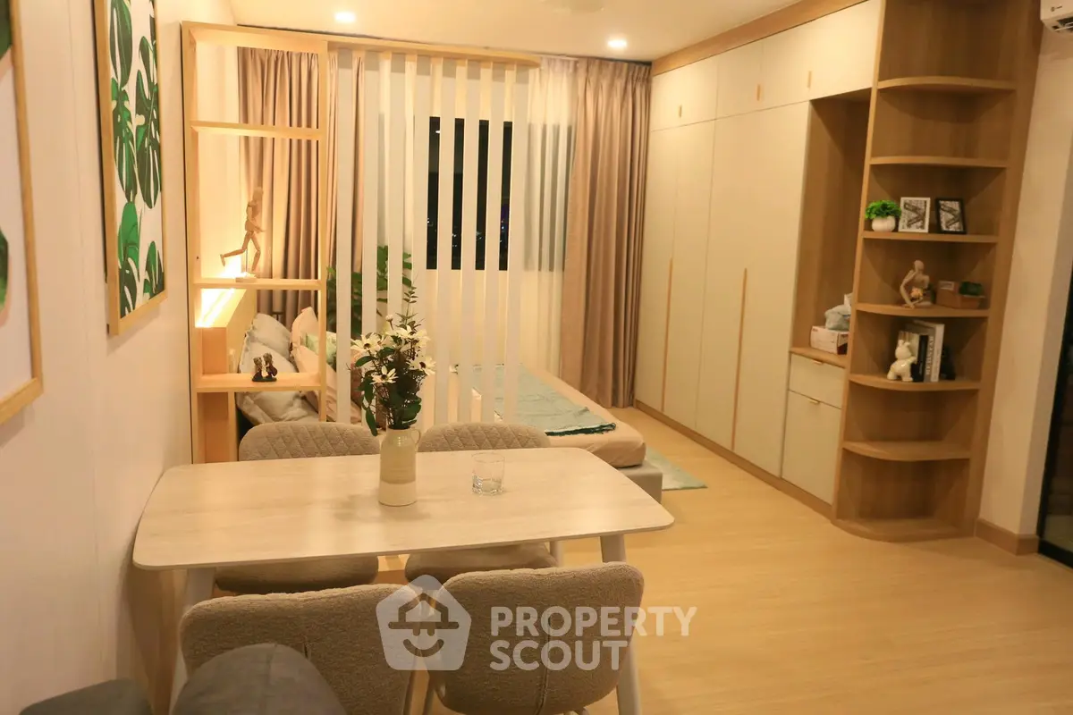 Modern open-plan living room with dining area and cozy bedroom in stylish apartment.