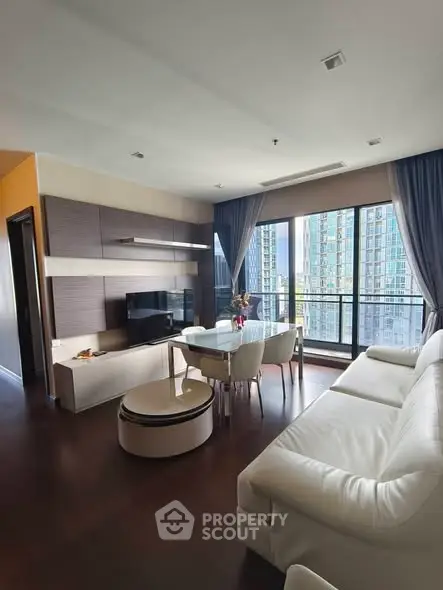 Modern living room with large windows and city view, featuring sleek furniture and elegant decor.