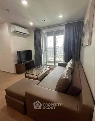 Modern living room with large sofa and balcony view in urban apartment.