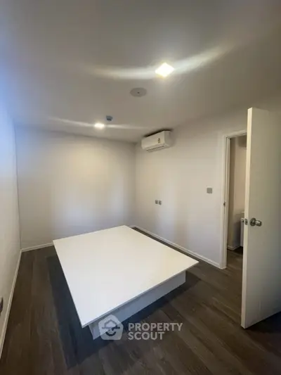 Minimalist bedroom with wooden flooring and air conditioning unit