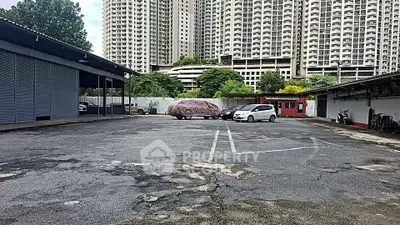 Spacious parking area with high-rise buildings in the background, ideal for urban living.