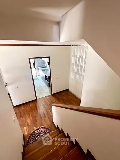 Elegant staircase with wooden flooring leading to a bright, open living space.