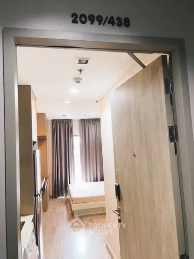 Modern apartment entrance with view into cozy bedroom and kitchen area.