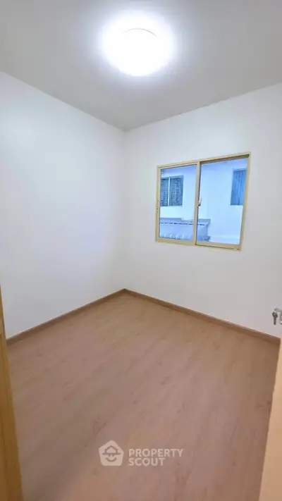 Minimalist empty room with wooden flooring and window view