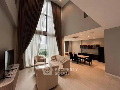 Luxurious high-ceiling living room with elegant furniture and large windows.
