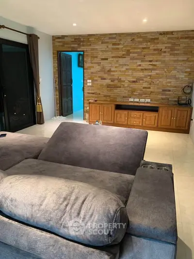 Spacious living room with cozy gray sofa and stylish brick accent wall.