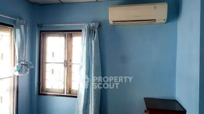 Cozy blue-walled room with air conditioning and natural light from windows.