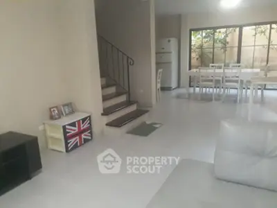 Spacious living area with dining space and staircase in modern home.
