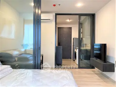 Modern bedroom with glass partition, sleek furniture, and in-unit laundry facilities.