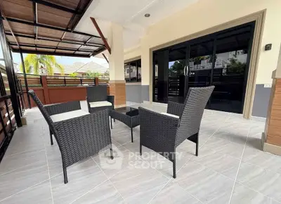 Spacious outdoor patio with modern wicker furniture and tiled flooring, perfect for relaxation.