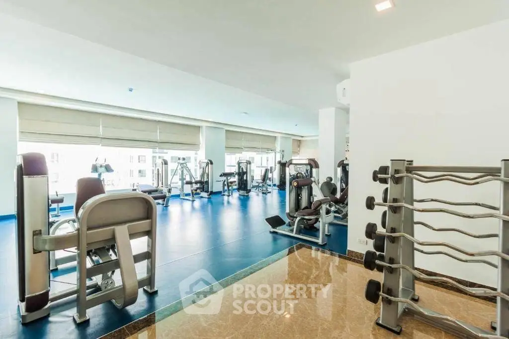 Spacious modern gym with state-of-the-art equipment and large windows for natural light.