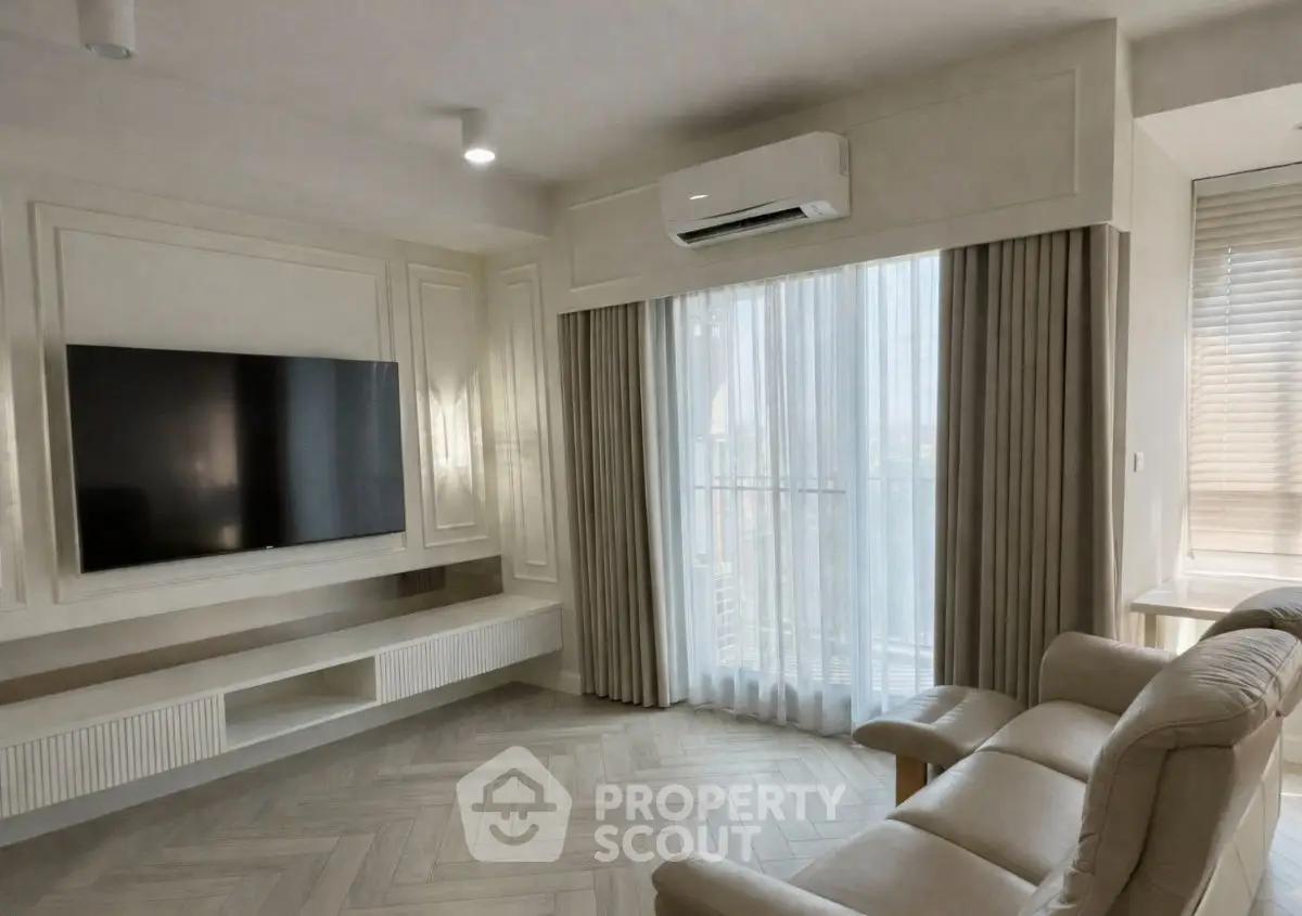 Elegant living room with modern TV setup and large window for natural light