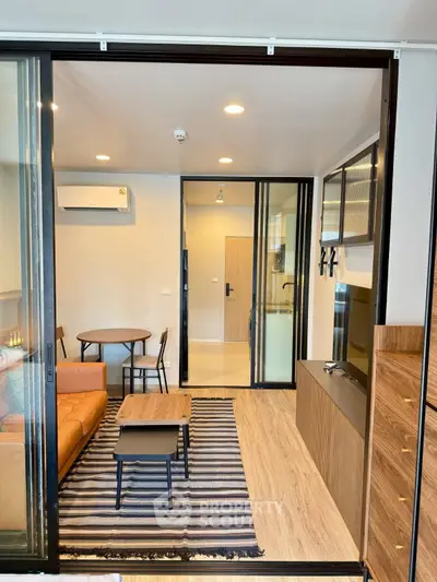 Modern living room with sliding glass doors, stylish furniture, and wood flooring in a contemporary apartment.
