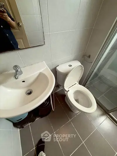 Compact bathroom with modern fixtures and tiled flooring, featuring a shower and toilet.