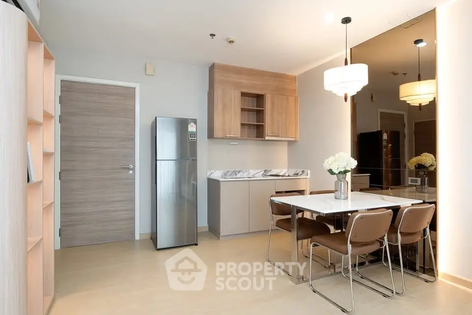 Modern dining area with wooden accents and stainless steel fridge in open layout kitchen.