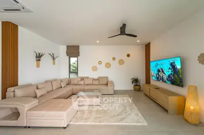 Spacious modern living room with beige sectional sofa, large TV, and stylish decor