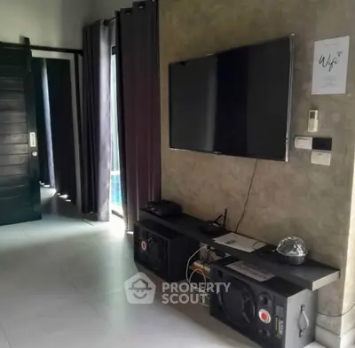 Modern living room with wall-mounted TV and sound system, featuring sleek decor and natural light.