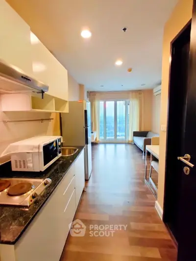 Modern studio apartment with open kitchen and city view, featuring sleek appliances and cozy living space.