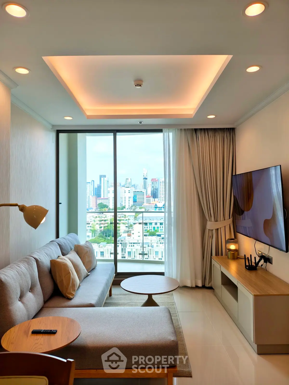 Modern living room with city view, featuring sleek furniture and large TV, perfect for urban living.