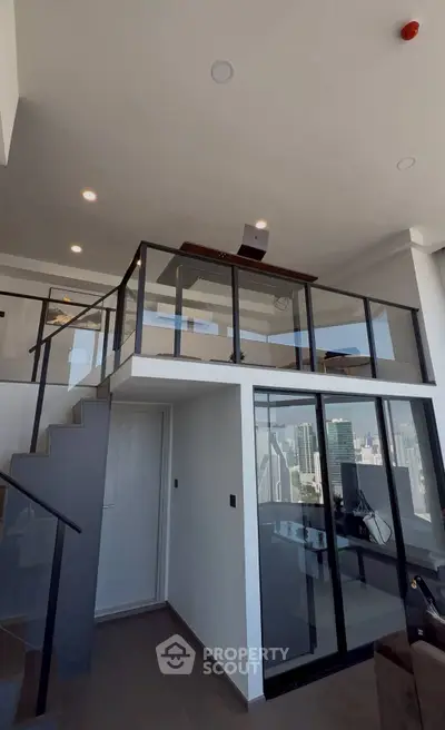 Modern loft apartment with mezzanine and city view, featuring sleek glass railings and contemporary design.
