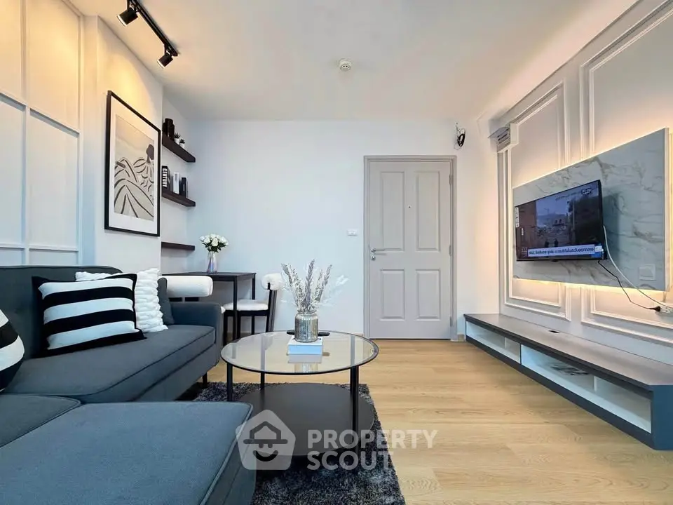 Modern living room with stylish decor and wall-mounted TV, featuring sleek furniture and elegant lighting.