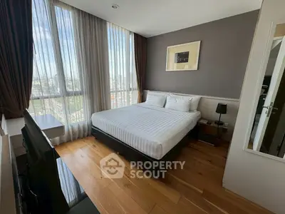 Modern bedroom with large windows and wooden flooring, offering a bright and inviting atmosphere.