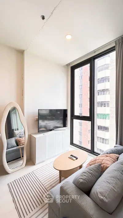 Modern living room with large window, stylish furniture, and cozy ambiance in urban apartment.