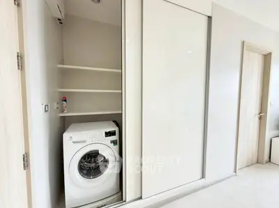 Modern laundry area with built-in washing machine and sliding door storage