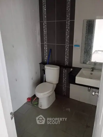 Compact bathroom with modern fixtures and tiled walls, featuring a toilet and sink.