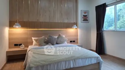 Modern bedroom with stylish decor and large window offering serene views.