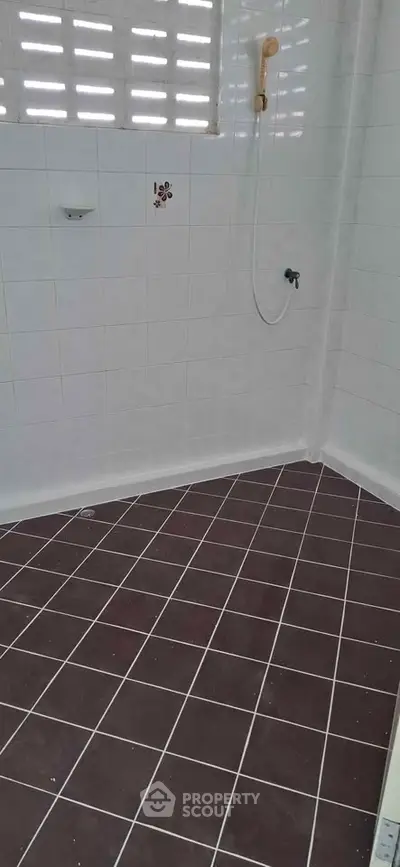 Spacious bathroom with tiled floor and wall-mounted shower in modern home.
