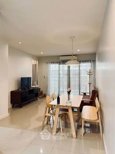 Modern living room with dining area, stylish furniture, and natural light through large windows.