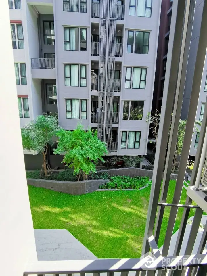 Modern apartment building with lush green garden view from balcony.